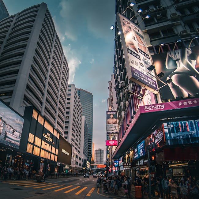 A bustling city street lined with skyscrapers and illuminated billboards at twilight.